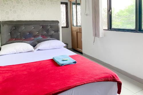 a bed with a red blanket on top of it at Penginapan Losmen Ayu Pamanukan RedPartner in Pamanukan-hilir