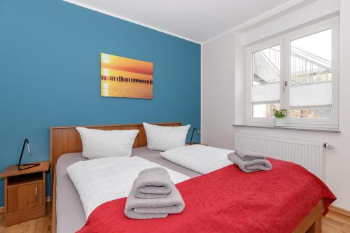 two beds in a bedroom with a red blanket at Appartementhaus Strandnähe in Warnemünde