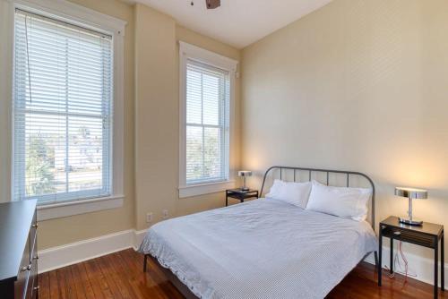 傑克孫維的住宿－Open & Bright - 5 min drive to TIAA Bank field，一间卧室配有一张带两张桌子和两个窗户的床。
