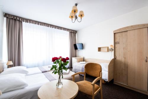 a hotel room with two beds and a table with flowers at Rewita Międzyzdroje Neptun in Międzyzdroje