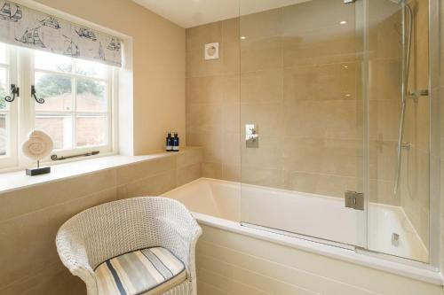a bathroom with a tub and a chair and a shower at 9 The Haven in Thorpeness