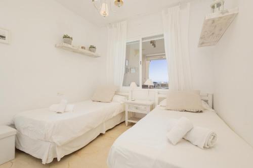 マルベーリャにあるBeautiful beachside duplex apartment with amazing sea viewsの白い部屋 ベッド2台 窓付