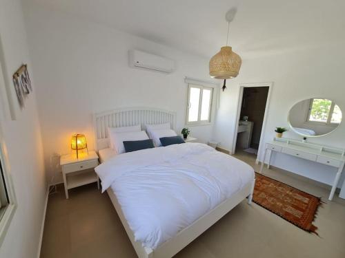 a white bedroom with a large bed and a mirror at Almaza Bay Beachtown Ground Chalet in Marsa Matruh