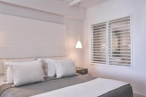 a bedroom with a bed with white walls and a window at Atlantica Aegean Park in Kolimbia