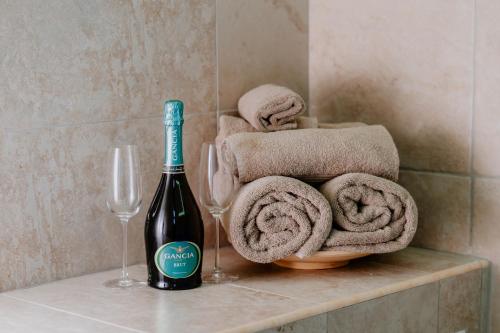 a bottle of wine sitting next to two wine glasses and towels at LUXUITE Spa con Piscina o Jacuzzi in Alberobello