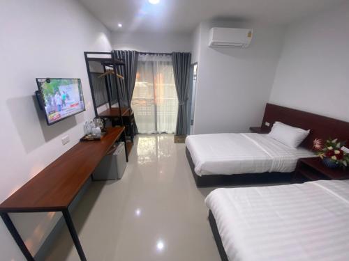 ein Hotelzimmer mit 2 Betten und einem TV in der Unterkunft SUPATTRA PLACE ( สุพัตราเพลส ) in Pai