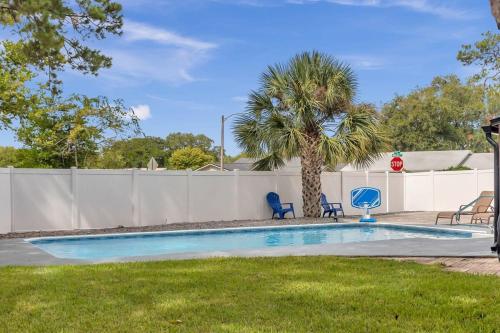 a swimming pool with two chairs and a palm tree at Spacious Home w Pool-Tucked Away in Jax Beach in Jacksonville Beach