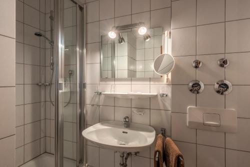 a bathroom with a sink and a shower and a mirror at Ferienwohnungen am Rathaus in Ruhpolding