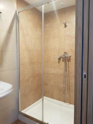 a shower with a glass door in a bathroom at VibesMuxía - Casa Rural Escola in Muxia