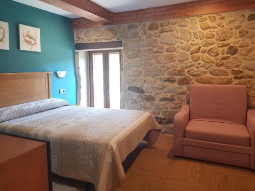 a bedroom with a bed and a chair at VibesMuxía - Casa Rural Escola in Muxia