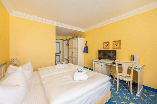a hotel room with two beds and a desk at Rugard Thermal Strandhotel in Binz