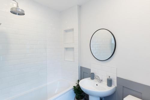 a white bathroom with a sink and a mirror at Oak Cottage in Deepcar