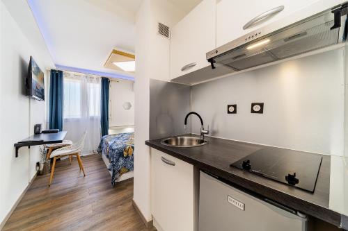 a kitchen with a sink and a bed in a room at Le studio du voyageur in Saint-Denis