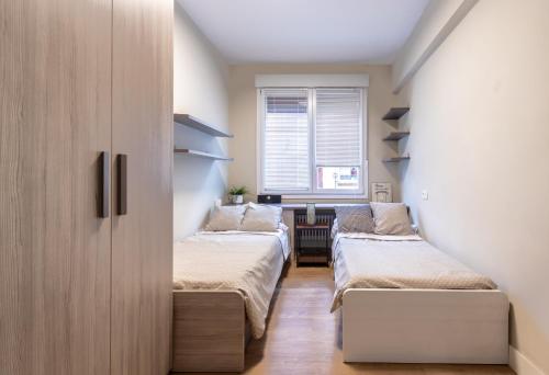 two beds in a small room with a window at Apartamento en Licenciado Poza in Bilbao