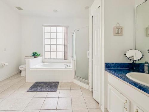 La salle de bains blanche est pourvue d'une baignoire et d'un lavabo. dans l'établissement Grand Luxury Deluxe 4BR Pool Home near Disney, à Davenport