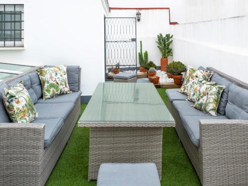 un patio con mesa y muebles de mimbre en Magno Apartments Almirante Hoyos House en Sevilla