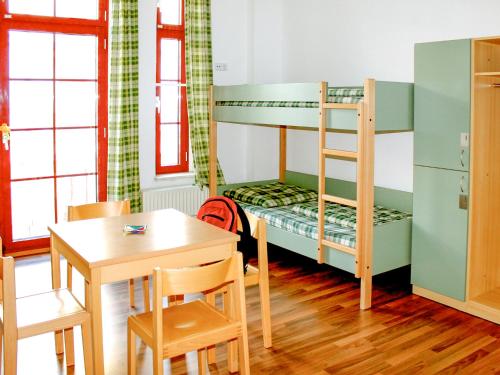 ライプツィヒにあるSleepy Lion Hostel & Apartments Leipzigのテーブルと二段ベッドが備わる客室です。
