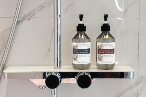 two bottles of alcohol sitting on a shelf in a bathroom at Yizhi Hotel Changgang Metro Station - Free Shuttle Bus during Canton Fair in Guangzhou