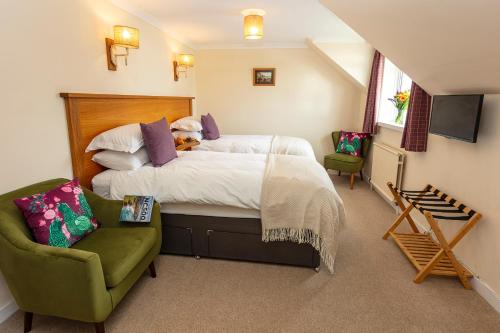 a bedroom with a bed and a green chair at Eilean Donan Guest House in Ullapool