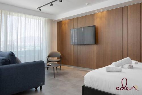 Habitación de hotel con cama y TV en la pared en סוויטה מעוצבת עם נוף מדהים לים - By Edomlux, en Eilat