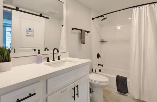 a white bathroom with a sink and a toilet at Fun Cozy 1 Br King Apts - 1 25 Mile Walk to TIAA Bnk Fld in Jacksonville