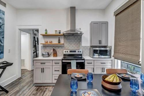 a kitchen with white cabinets and a table with chairs at Contemporary Apartment - 5 Min To TIAA Bank Field! in Jacksonville