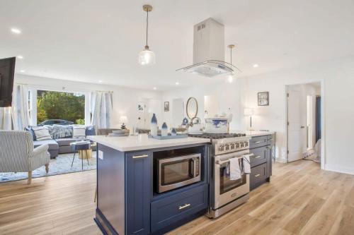 a kitchen with a stove and a living room at Stylish + fresh bungalow 2 blocks from N-MC Stadium in Annapolis