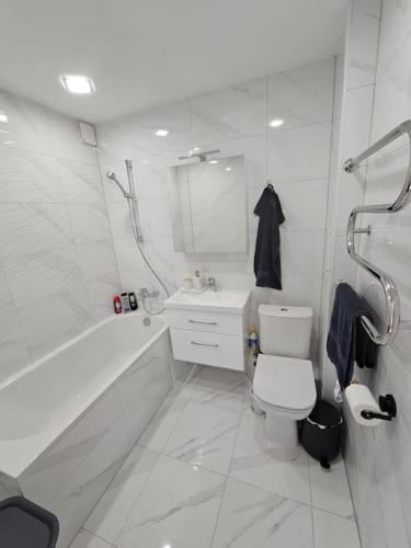 baño blanco con bañera, aseo y lavamanos en Gražus ir ramus butas jonavoje en Jonava