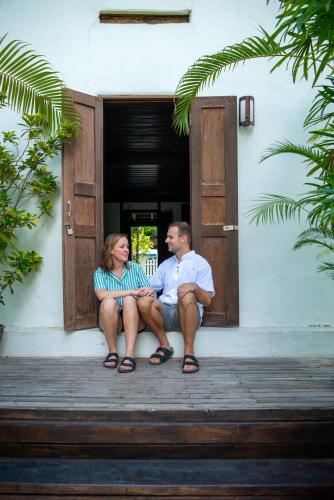 a man and woman sitting on the porch of a house at 3 Nagas Hotel Luang Prabang - MGallery Collection in Luang Prabang