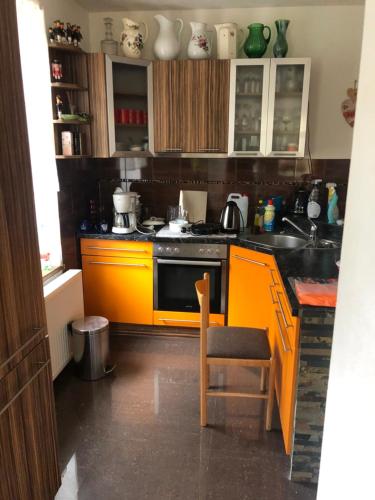 an orange kitchen with a stove and a chair at Die Blauer Stern Weipert in Chomutov