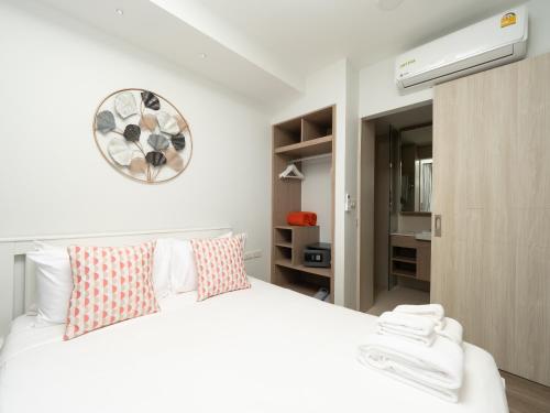 a bedroom with a white bed and a clock on the wall at Family 2bd apartments in Laguna SkyPark in Bang Tao Beach