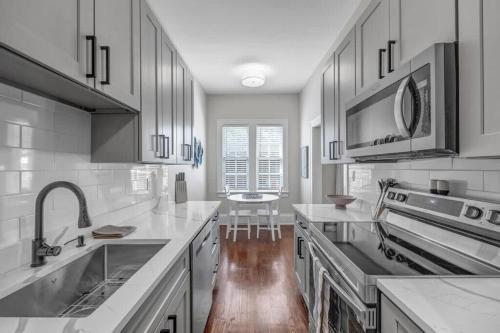 cocina con armarios blancos, fregadero y encimera en Renovated Apt - Blocks from Shoppes of Avondale, en Jacksonville