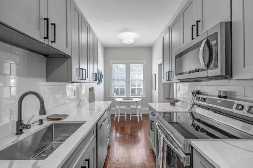 a kitchen with white cabinets and a sink and a counter at Renovated Apt - Blocks from Shoppes of Avondale in Jacksonville