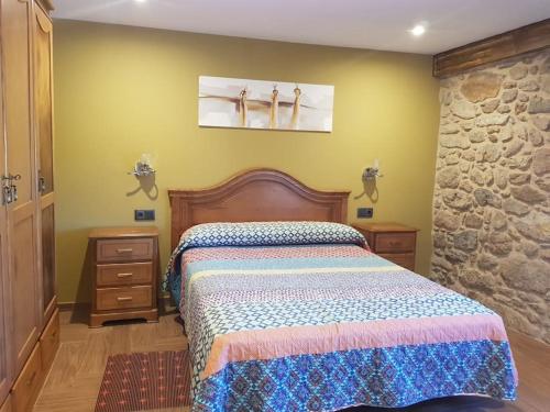 a bedroom with a bed and a stone wall at VibesMuxía -Casa Rural Corredoira in Muxia