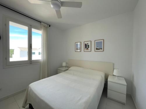 a white bedroom with a bed and a window at ALBATROS 48 by SOM Menorca in Son Parc