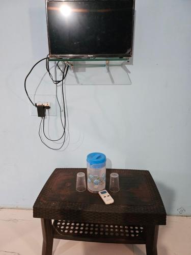een houten tafel met een televisie aan de muur bij New Aashiyana Cottage in Matheran