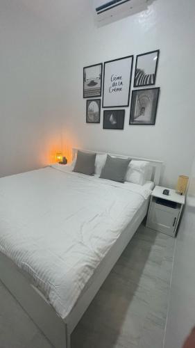 a white bed in a room with pictures on the wall at Saphir Townhouse 5 to 6 pax rooftop terrace, Cavite in Imus