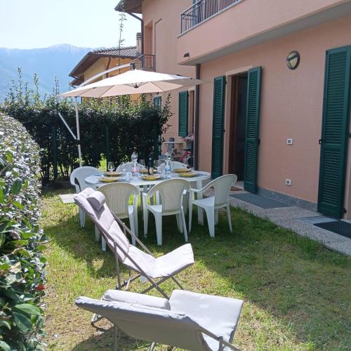 an outdoor table with chairs and an umbrella at La casa al lago BMOR love&lake in Mezzegra