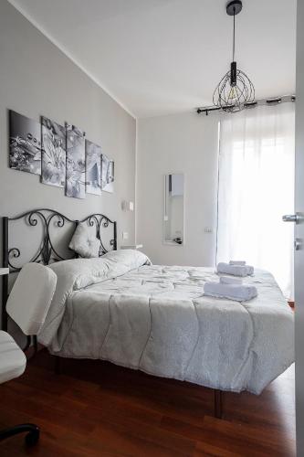 a white bedroom with a large bed and a chandelier at Casa di Ale in Tivoli
