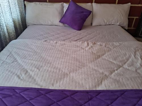 a bed with purple and white sheets and pillows at Royal homes a5 in Kushālnagar