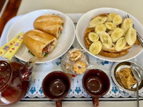 a tray with three plates of food with a sandwich and bananas at Cherry Homestay - Hoàng Đế motel in Chau Doc