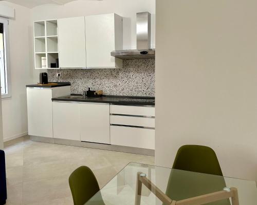 a kitchen with white cabinets and a glass table at MONO Apartments Aldini in Bologna