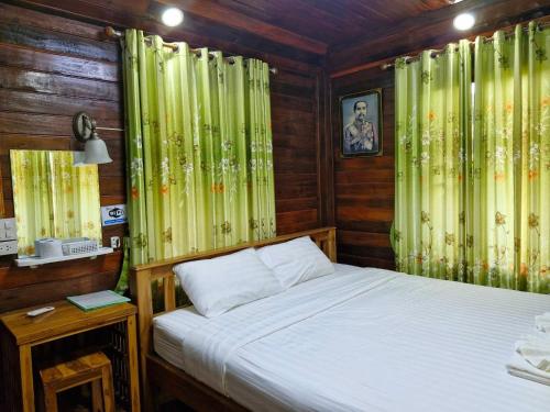 Schlafzimmer mit einem Bett und grünen Vorhängen in der Unterkunft Yungthong Baan Suan Resort in Ban Ko