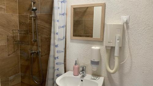 a bathroom with a sink and a shower with a mirror at Toscan Panzió in Gyál