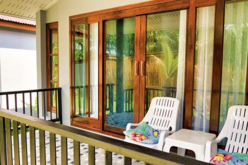 a porch with two white chairs and glass doors at Seaside Sanctuary Bungalows in Ko Lanta