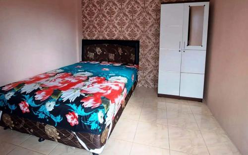 SPOT ON 93880 Guest House Bu Iin Syariah في سيدوارجو: غرفة نوم مع سرير وبطانية ملونة