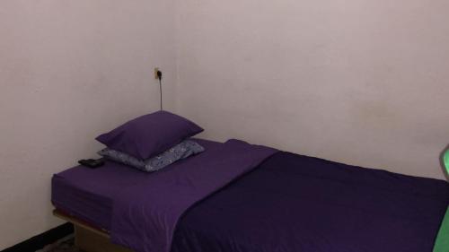 a bed with purple sheets and a pillow at OYO 93846 Gerlong Homestay in Bandung