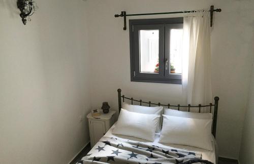 a bedroom with a bed with white pillows and a window at Ferienhaus Triandafilo in Pythagoreio