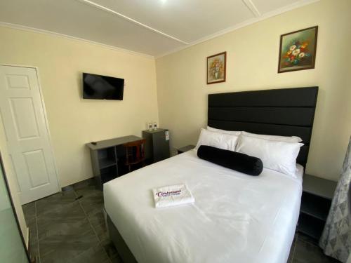 a bedroom with a white bed with a black headboard at Cumberland Guest Lodge in Bulawayo