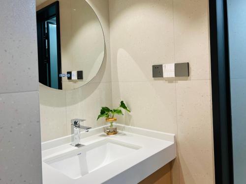 a bathroom with a white sink and a mirror at Stylish 3 RMs city APT, with laundry sets, Easy to go main locations in Zhangjiajie
